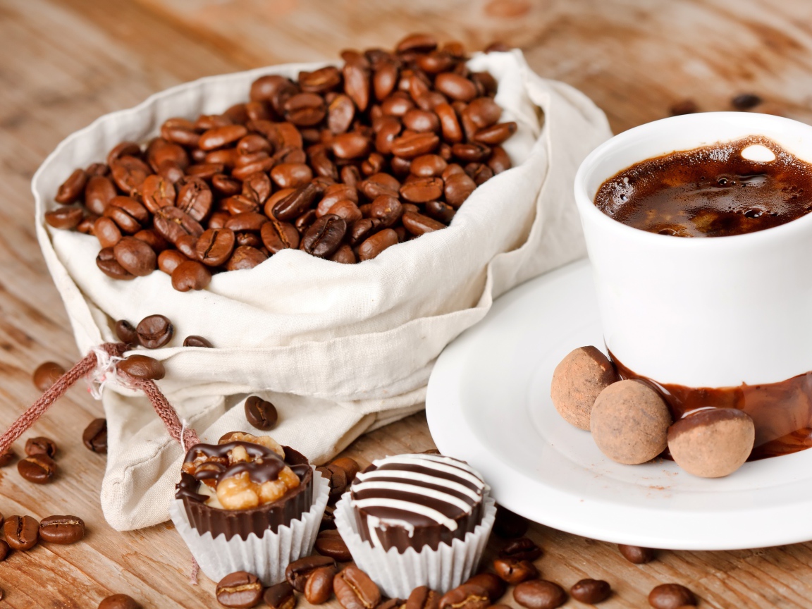 Шоколадные конфеты на столе с чашкой кофе и мешком с кофейными зернами