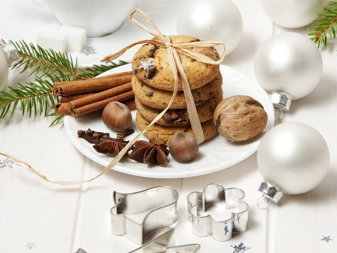 Печенье на тарелке с орехами и корицей на столе с игрушками 