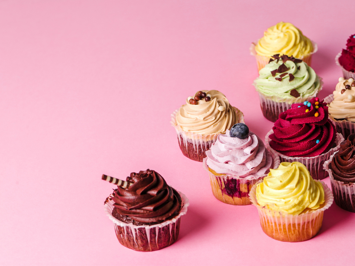 Кексы с разноцветным кремом на розовом фоне