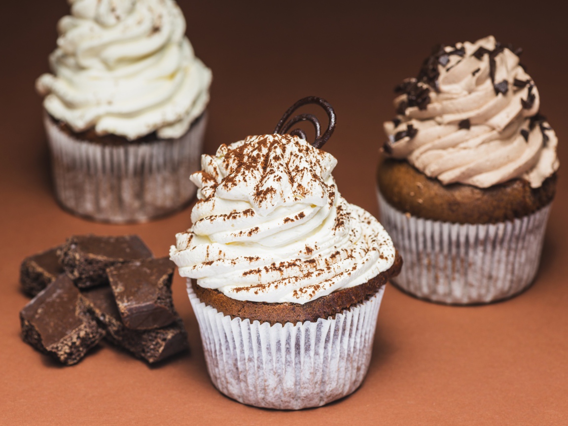 Кексы с кремом на столе с кусочками шоколада 