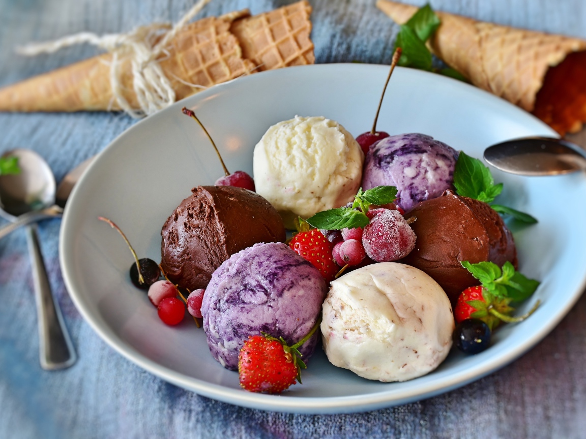 Шарики фруктового мороженого на тарелке со свежими ягодами