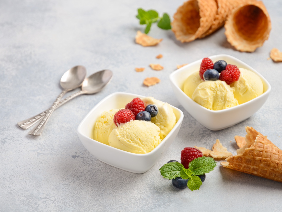 Шарики мороженого с ягодами на столе с вафельными рожками