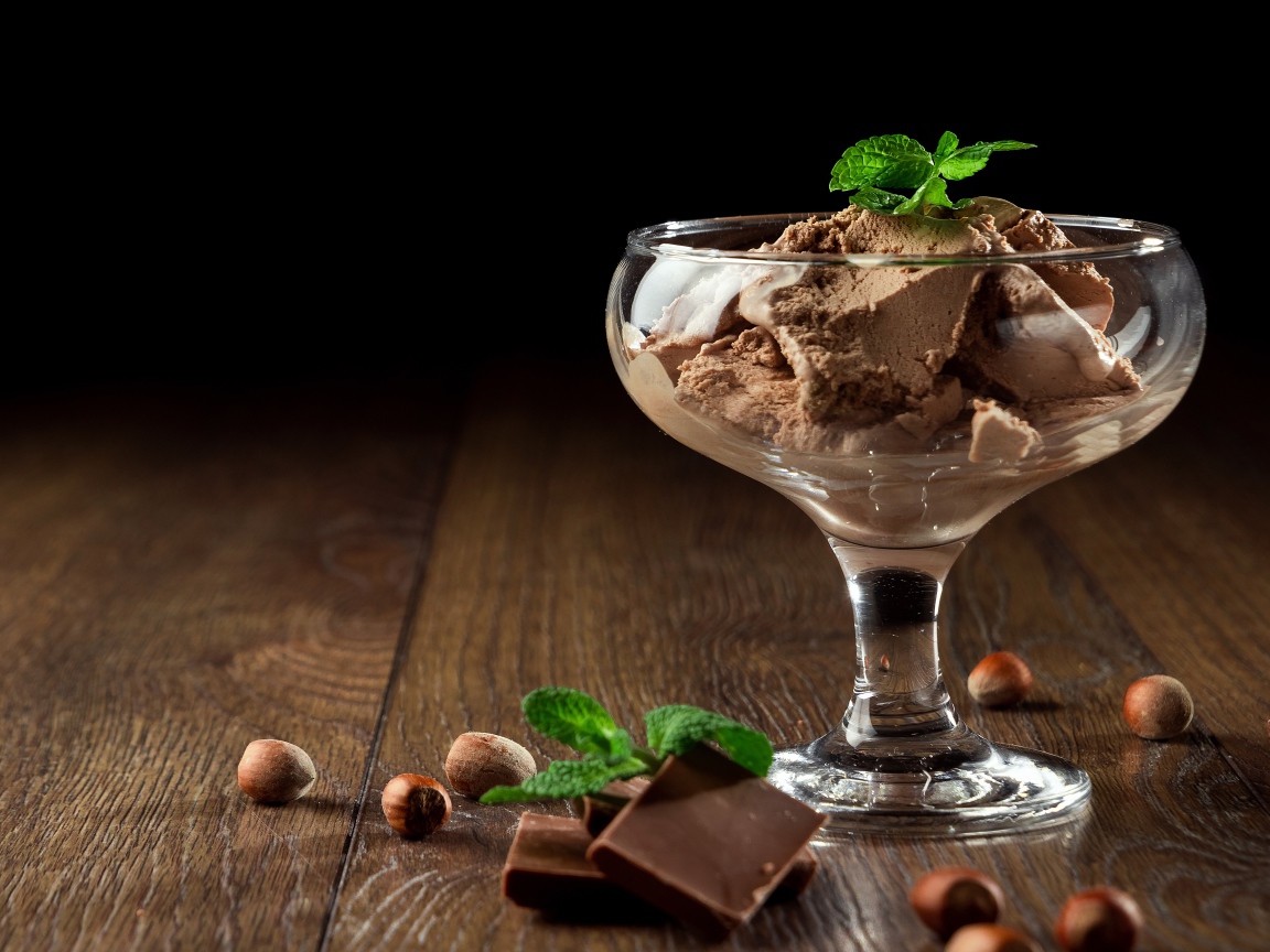 Кофейное мороженое в креманке на столе с шоколадом и орехами