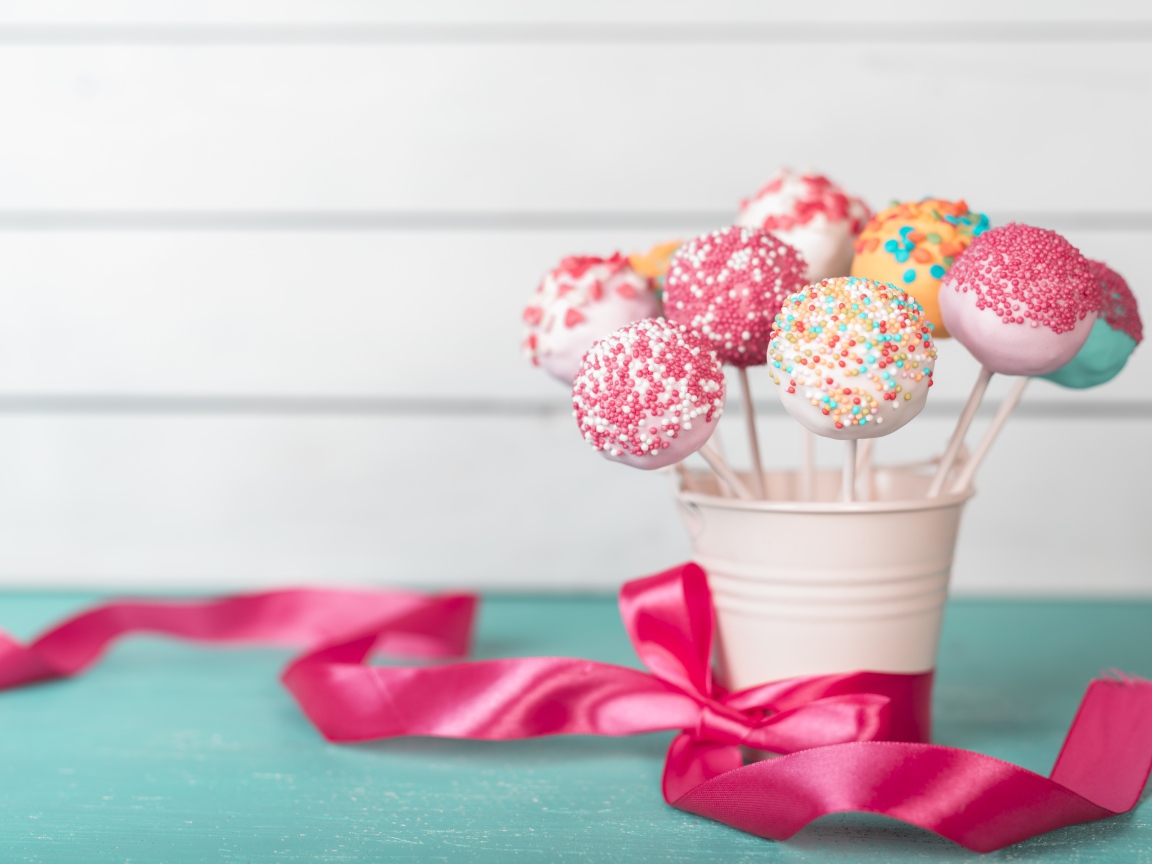 Леденцы в стакане на столе с розовым бантом из ленты