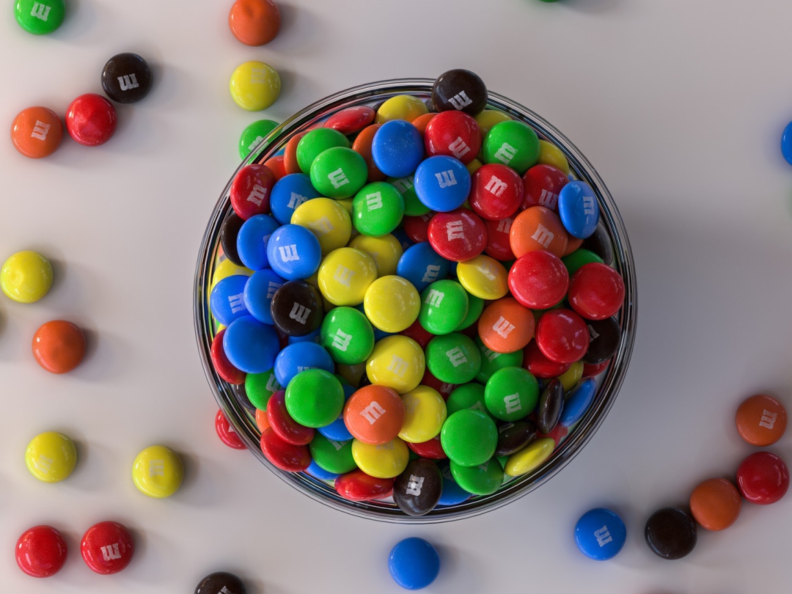 Разноцветные конфеты с миске на сером столе