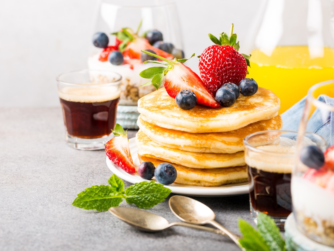 Оладьи с ягодами на столе с соком