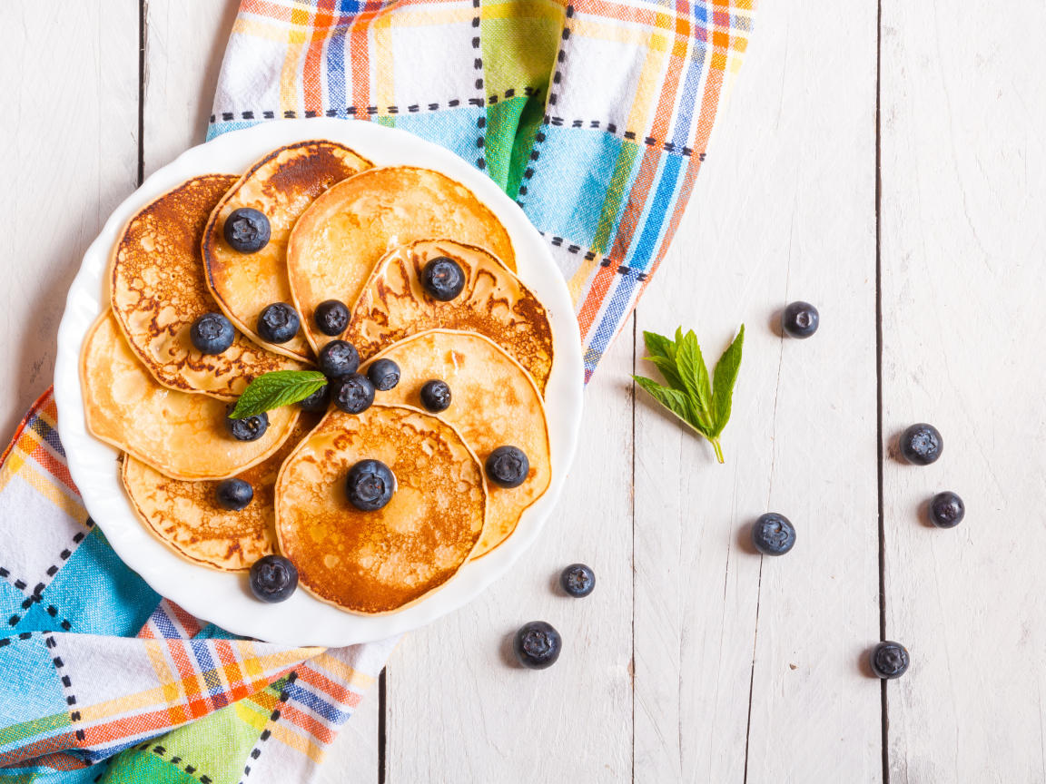 Румяные оладьи на тарелке с ягодами черники