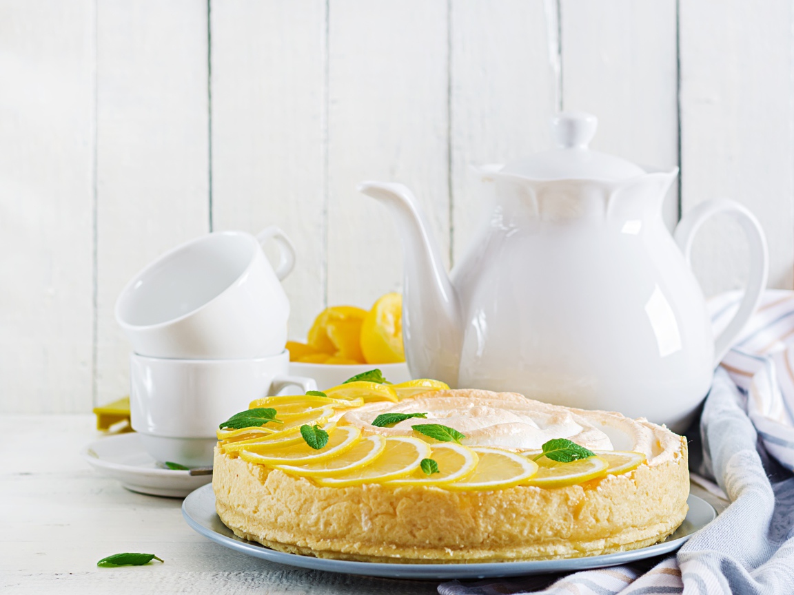 Вкусный песочный пирог с лимоном на столе с чашками и чайником