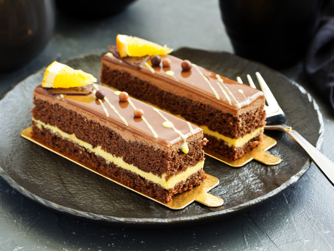 Два вкусных шоколадных пирожный на большой тарелке с вилкой