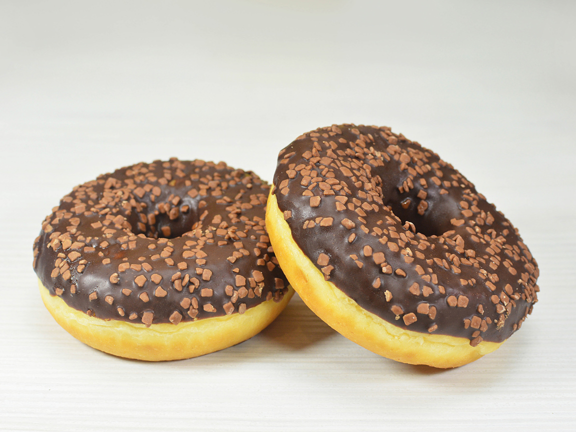 Два сладких пончика с шоколадом на сером фоне