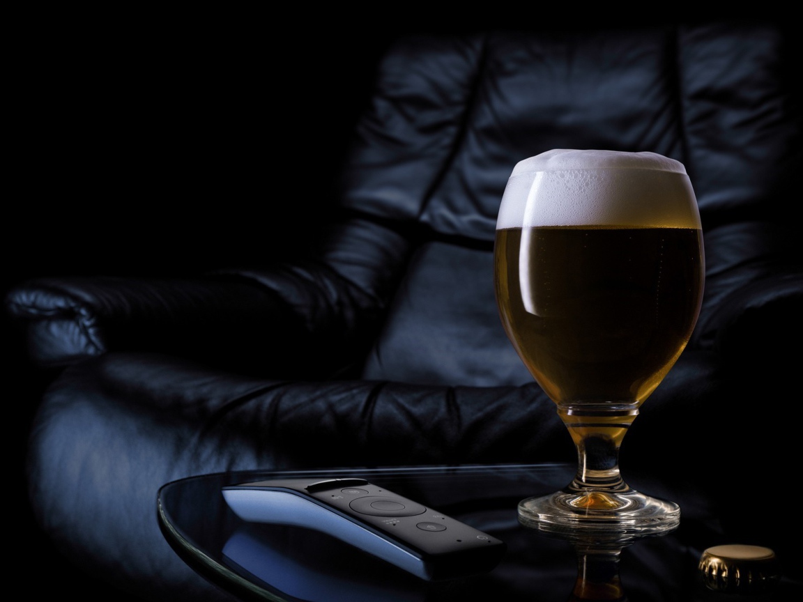 Бокал пива на фоне черного кожаного кресла