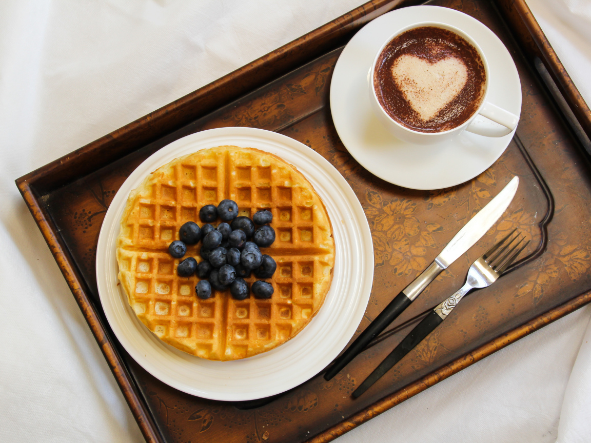 Капучино в чашке на подносе с вафлями и черникой 