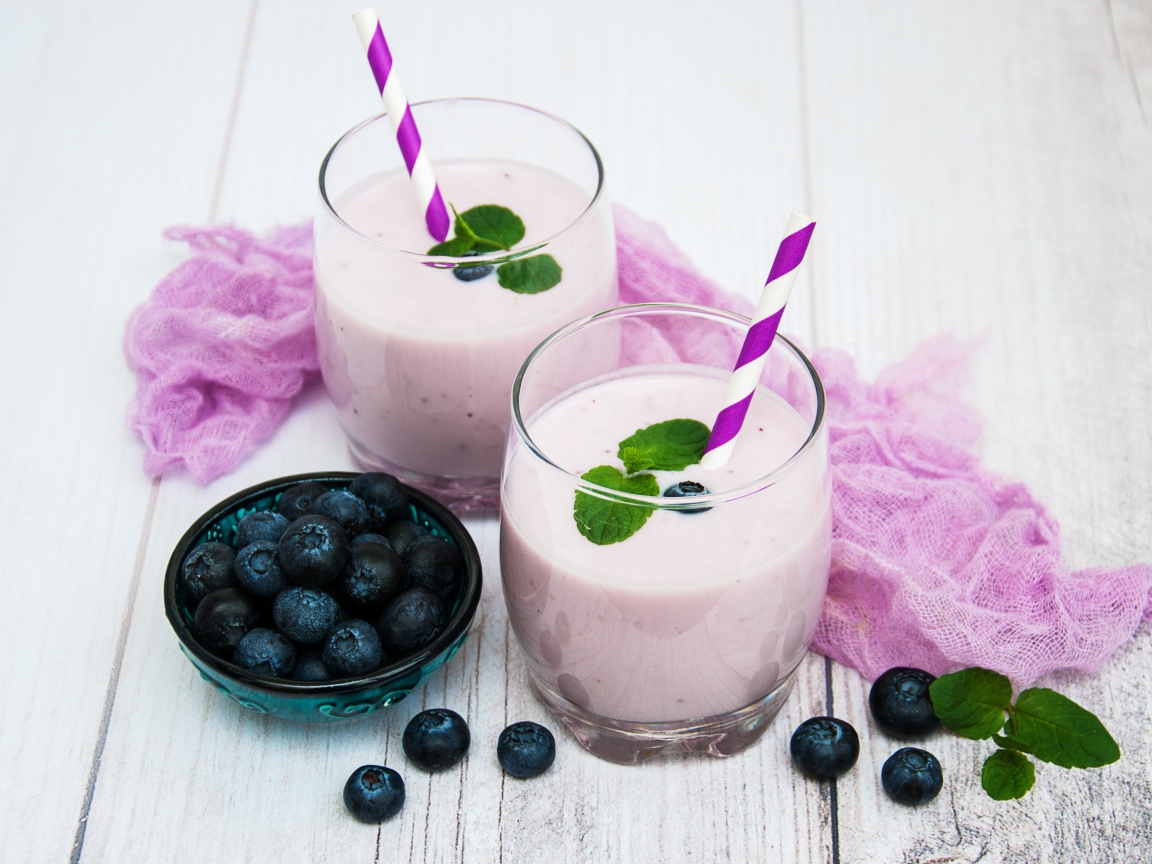 Коктейль в стаканах на столе с ягодами черники