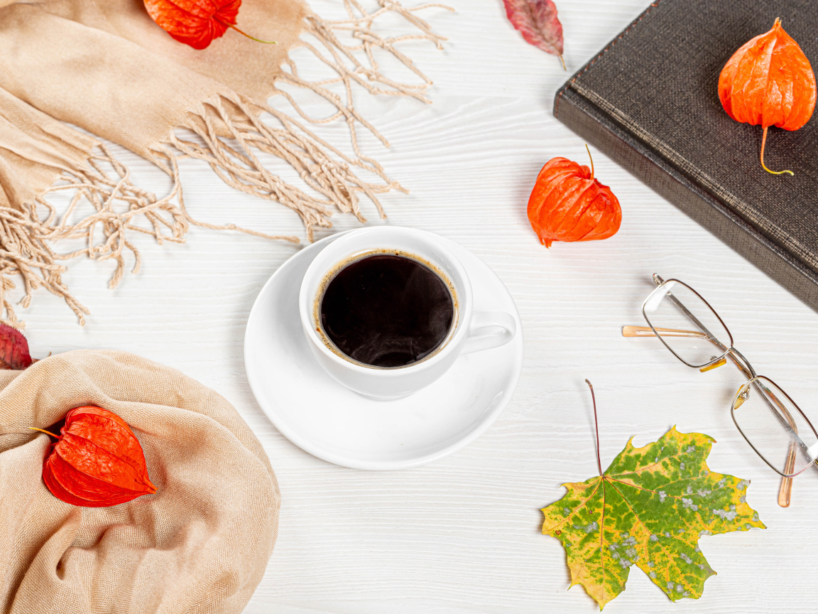 Чашка кофе на столе с книгой, очками и физалисом