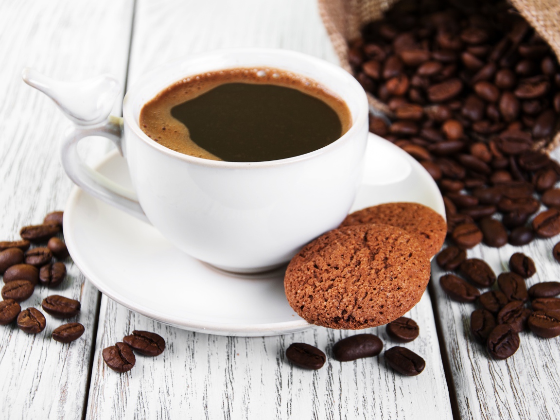 Чашка кофе на столе с кофейными зернами и печеньем