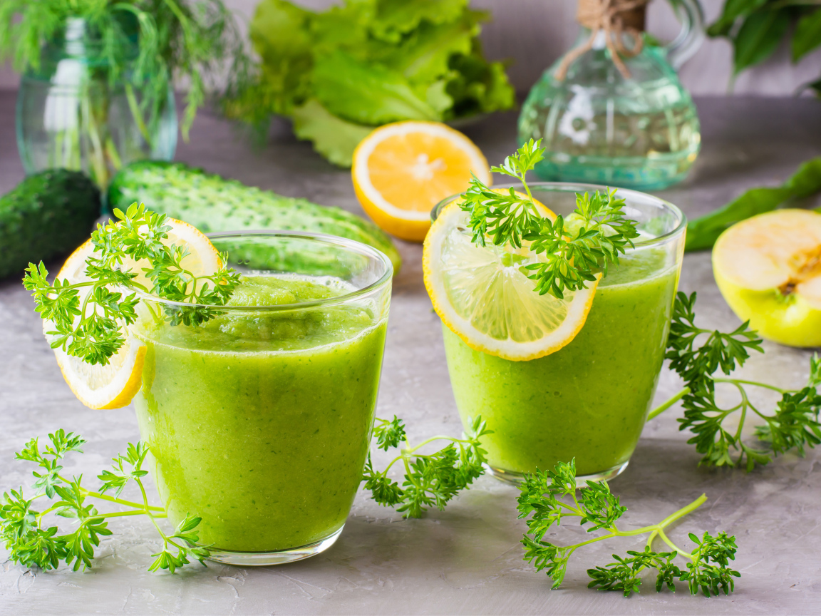 Зеленый смузи в стаканах с кусочками лимона и петрушкой