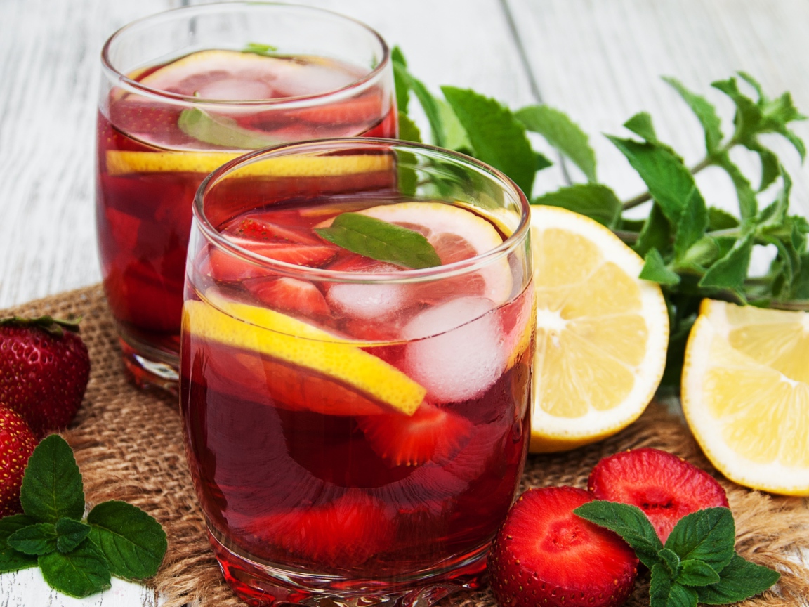 Мохито в стаканах на столе с клубникой, лимоном и мятой