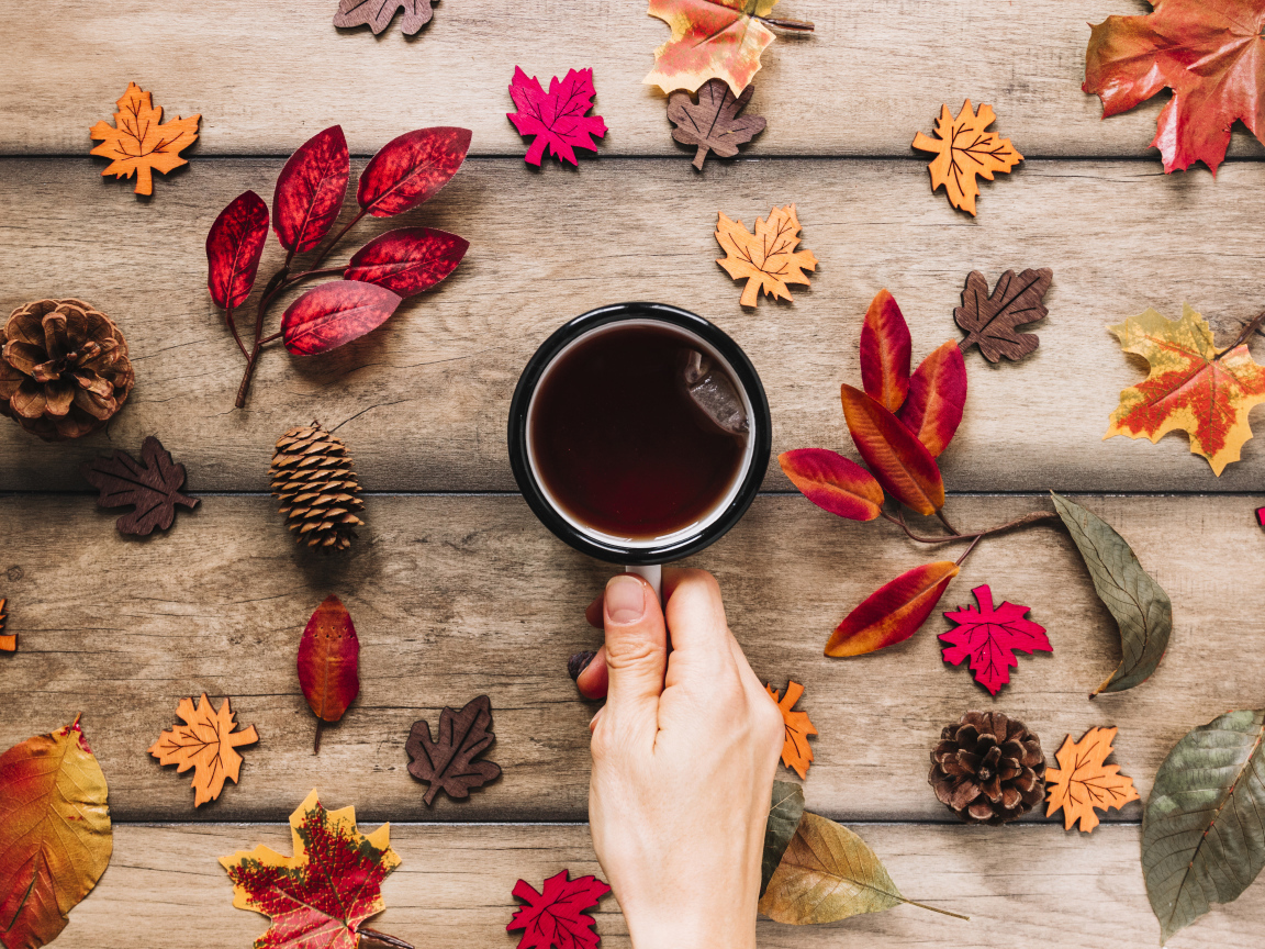 Кружка чая на столе с осенними листьями
