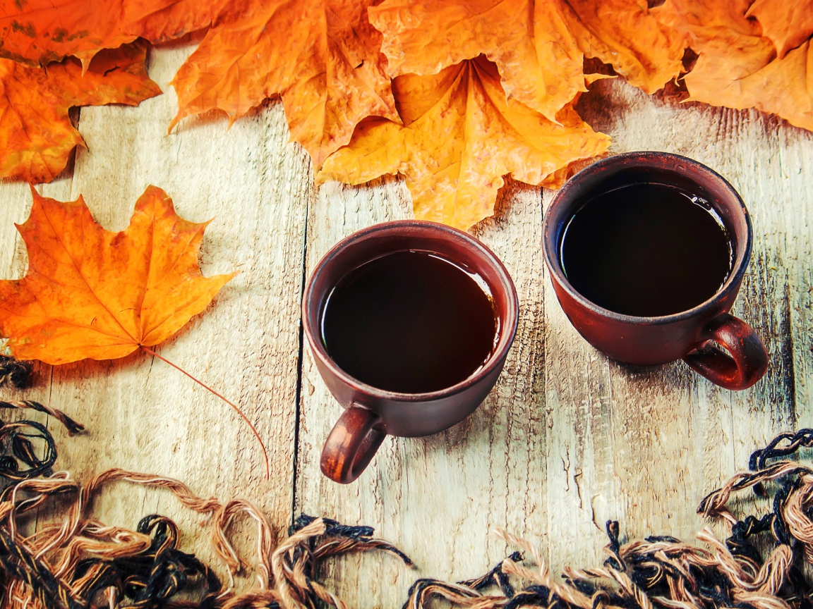 Две чашки горячего кофе на столе с сухими листьями