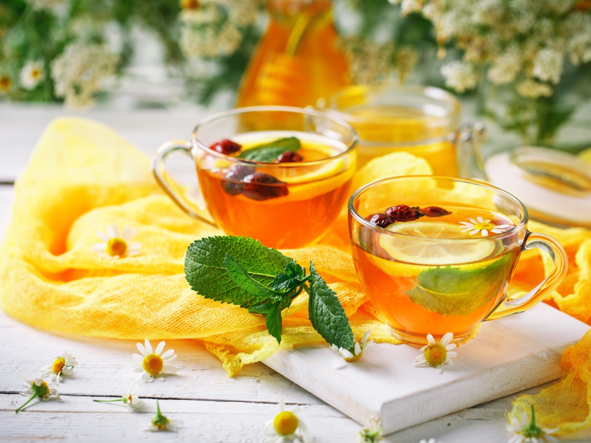 Две стеклянные чашки чая с лимоном, мятой и шиповником