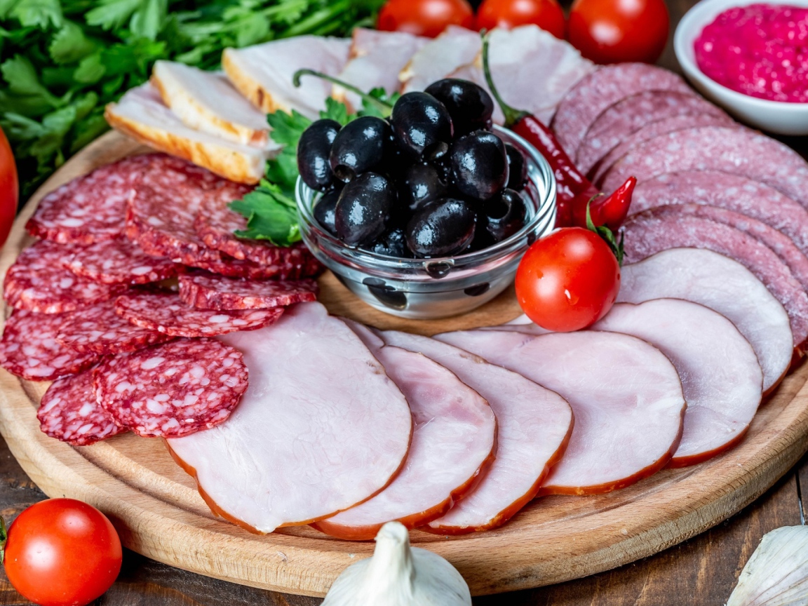 Колбасные продукты на доске с оливками