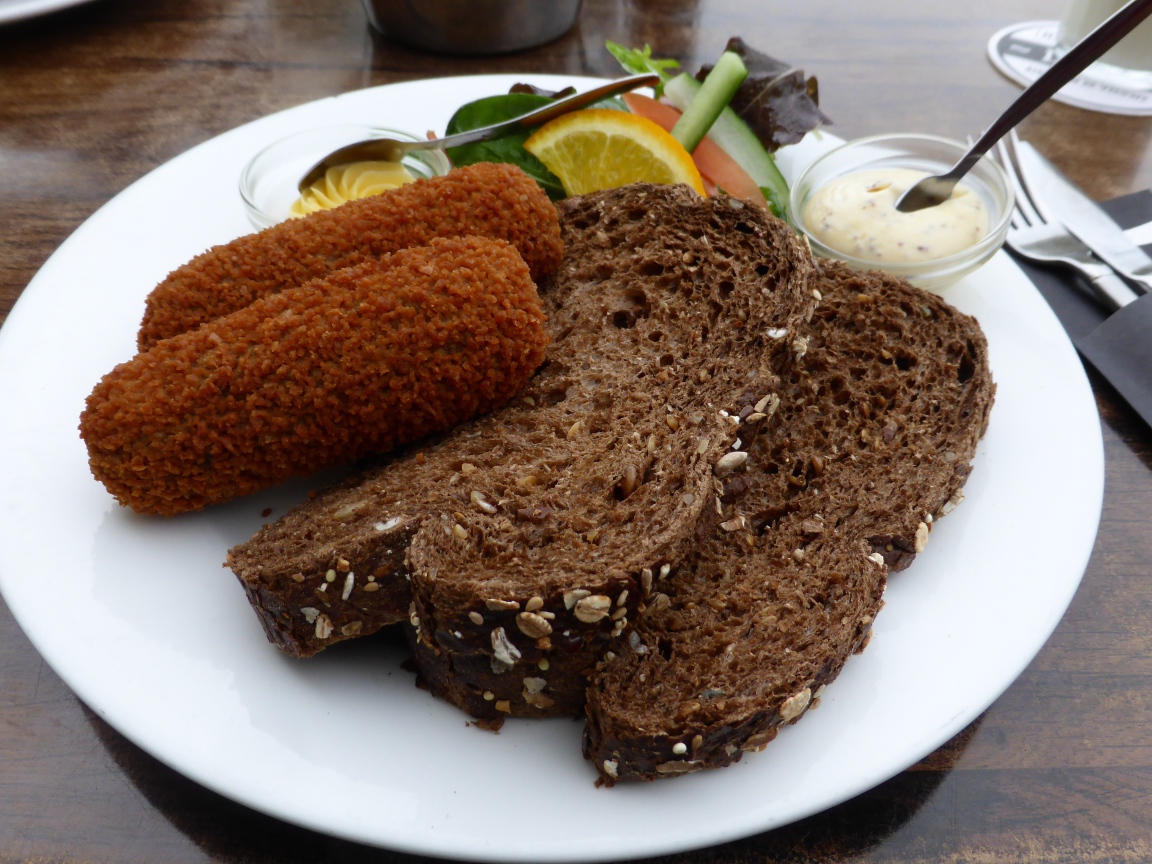 Два куска черного хлеба на тарелке с котлетами