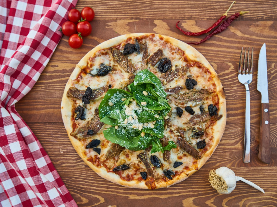 Пицца с мясом и шпинатом на столе 