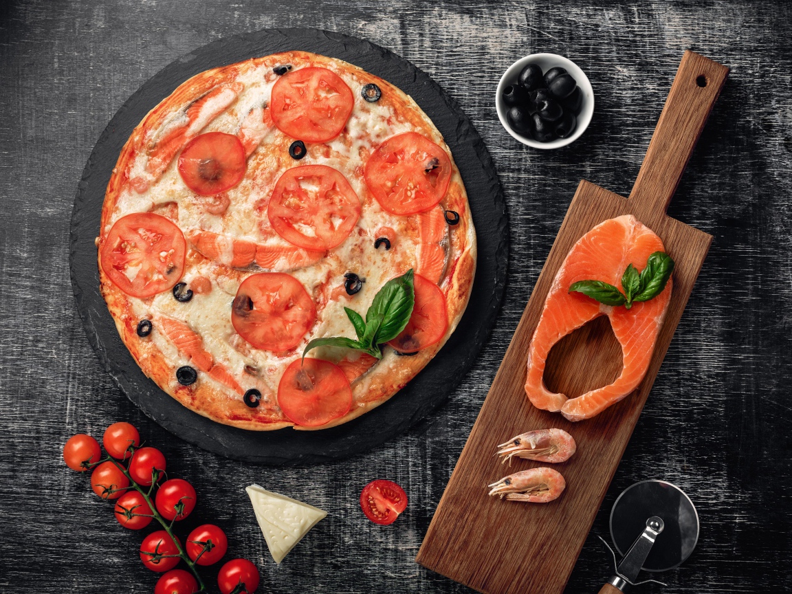 Пицца с помидорами, красной рыбой и сыром на столе 