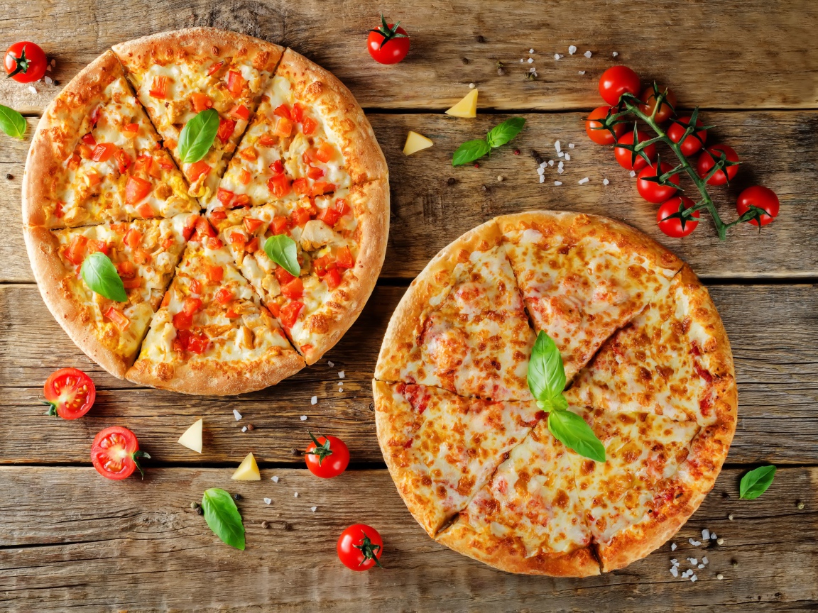 Две пиццы с сыром и болгарским перцем на столе с помидорами