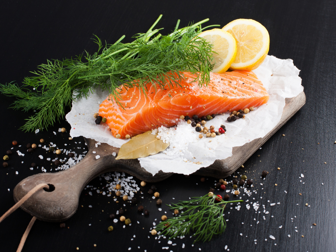 Кусок красной рыбы на доске с укропом и лимоном 