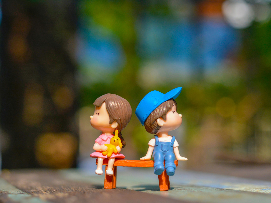 Two little toys a boy and a girl on the bench