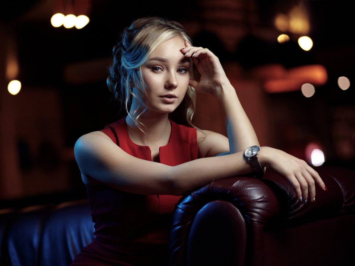 Красивая девушка с часами на руке сидит в кресле