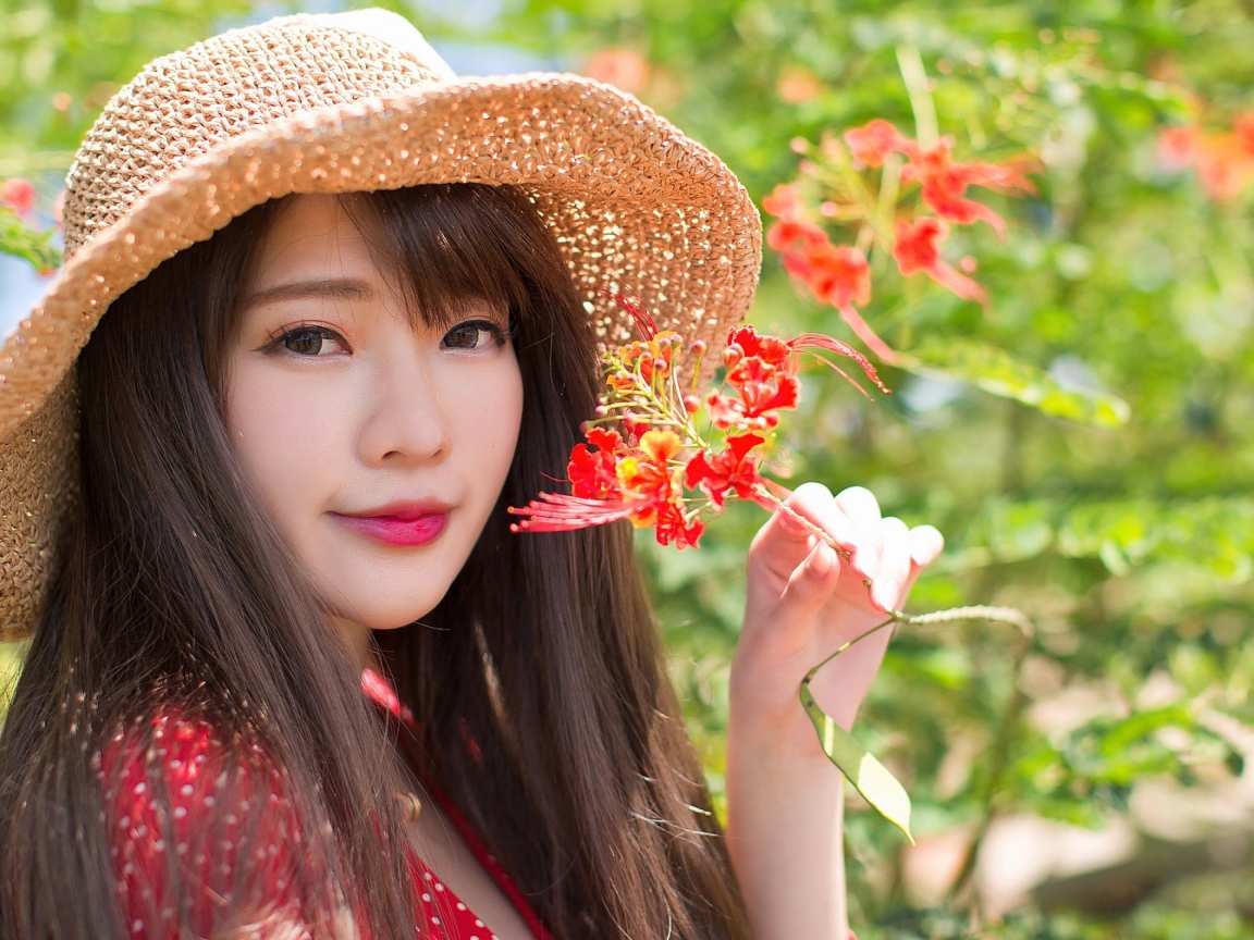 Девушка азиатка в шляпе с красным цветком