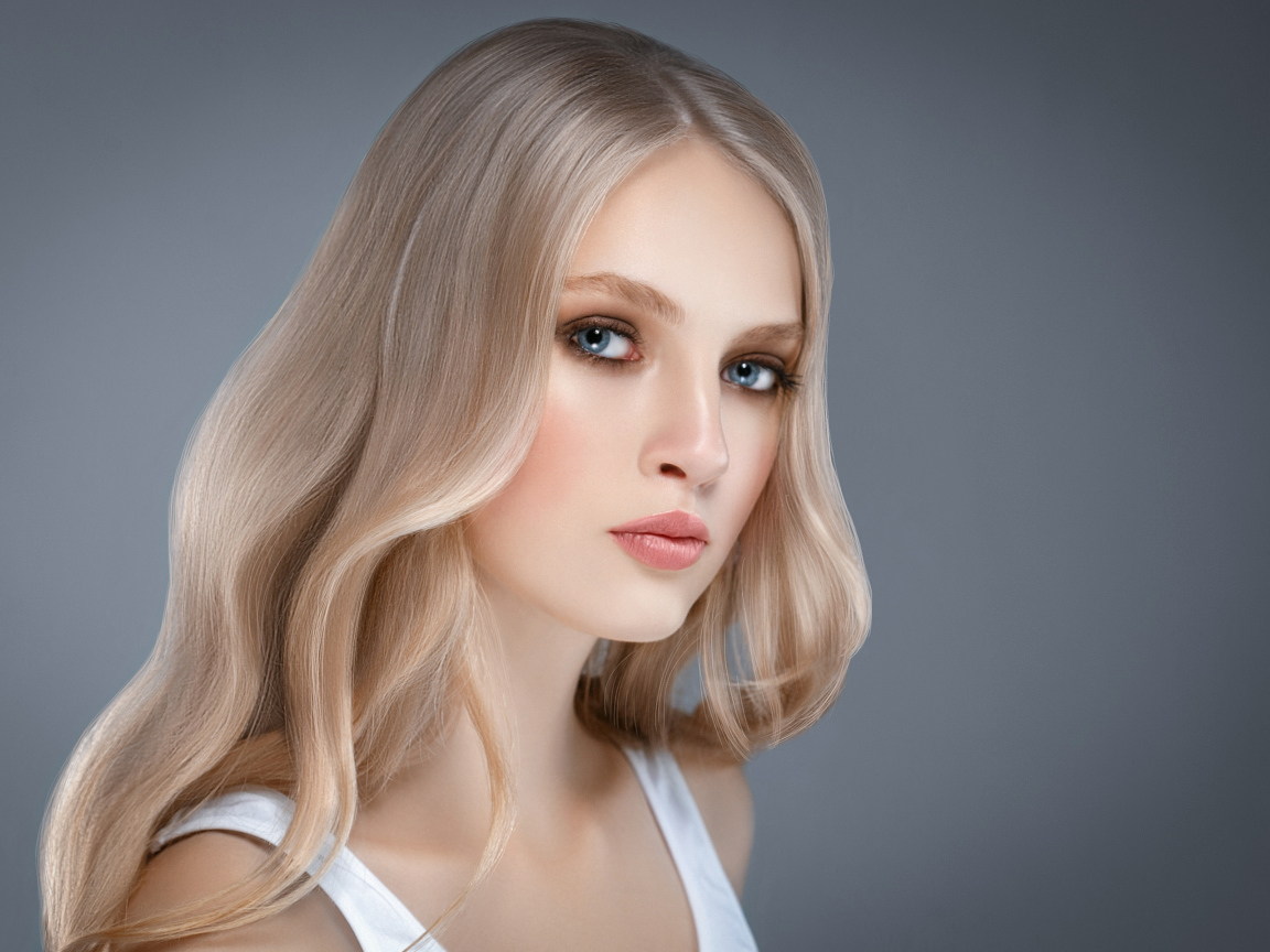 Красивая нежная голубоглазая блондинка на сером фоне