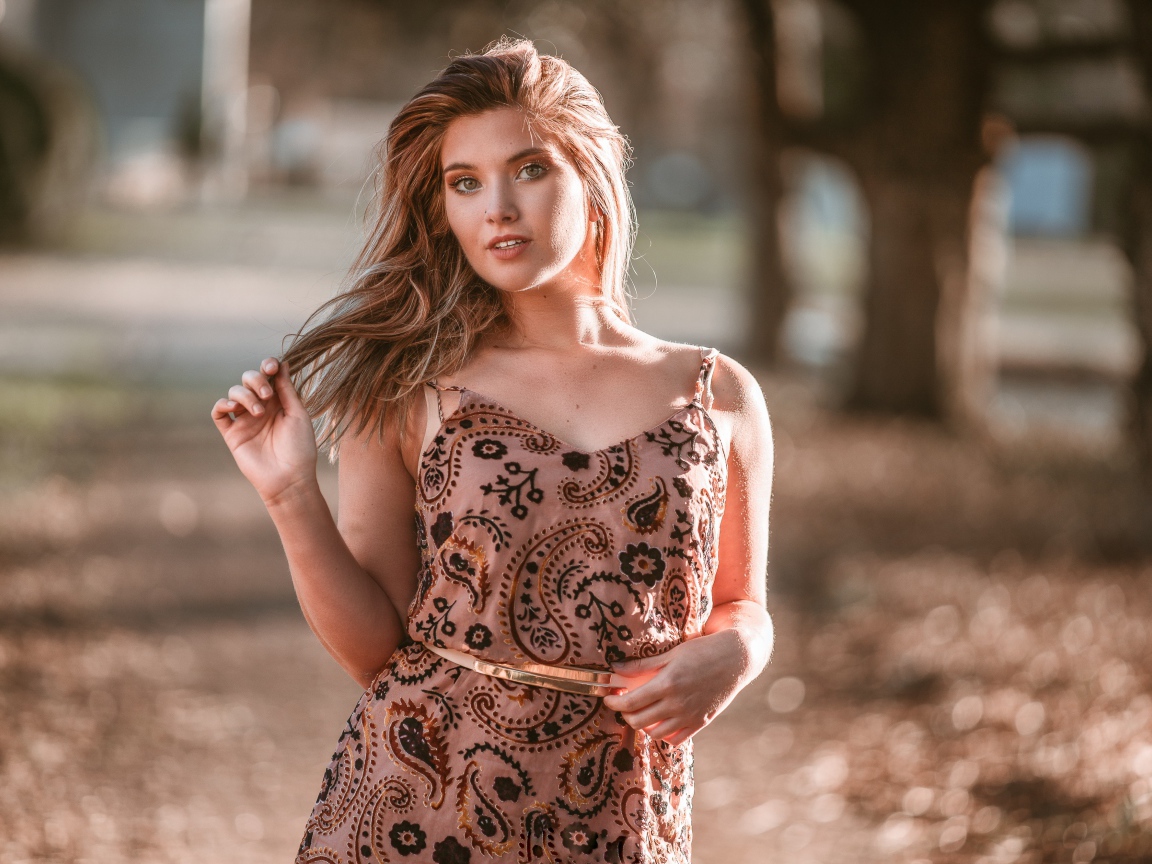 Красивая девушка в платье в лучах солнца летом