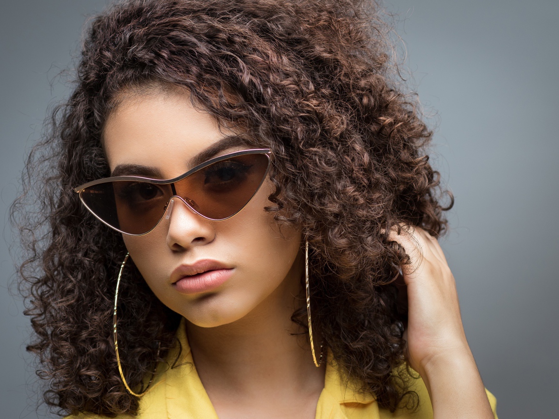 Красивая девушка в солнечных очках на сером фоне