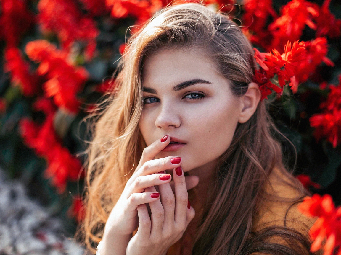 Красивая девушка на фоне красных цветов