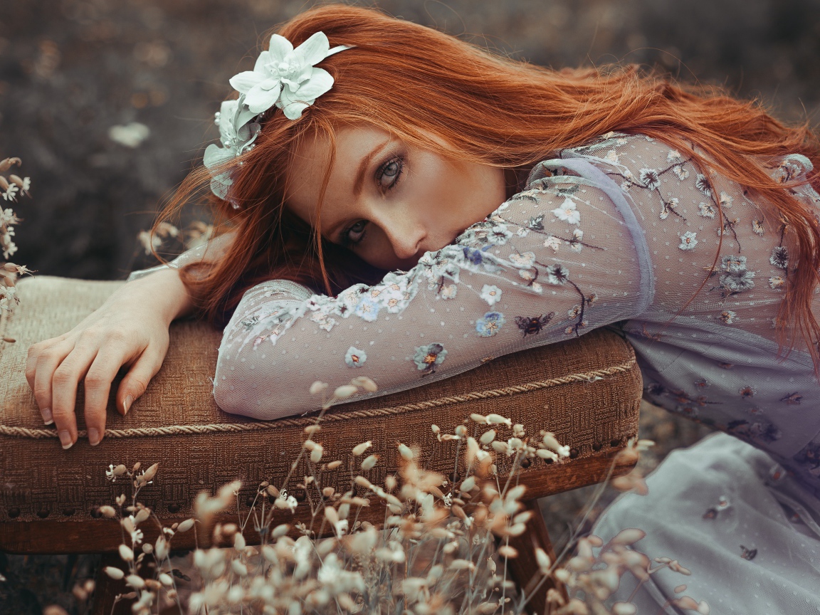 Красивая рыжеволосая девушка лежит на стуле