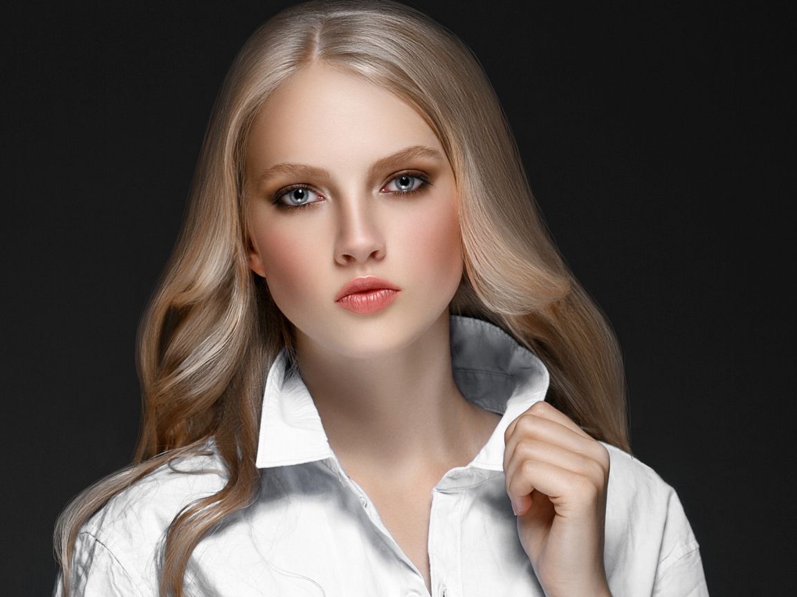 Красивая стильная голубоглазая блондинка в белой рубашке на сером фоне