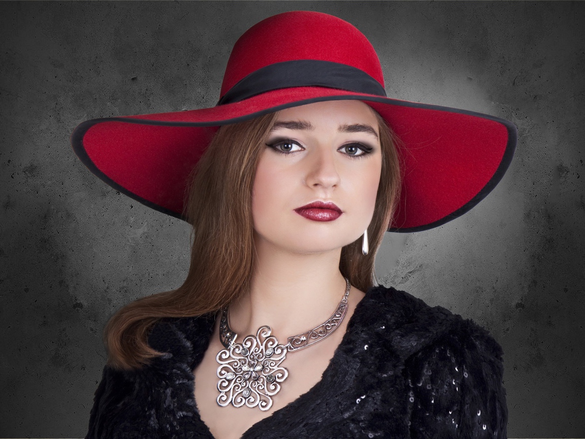 Красивая стильная девушка в красной шляпе с украшением на шее 