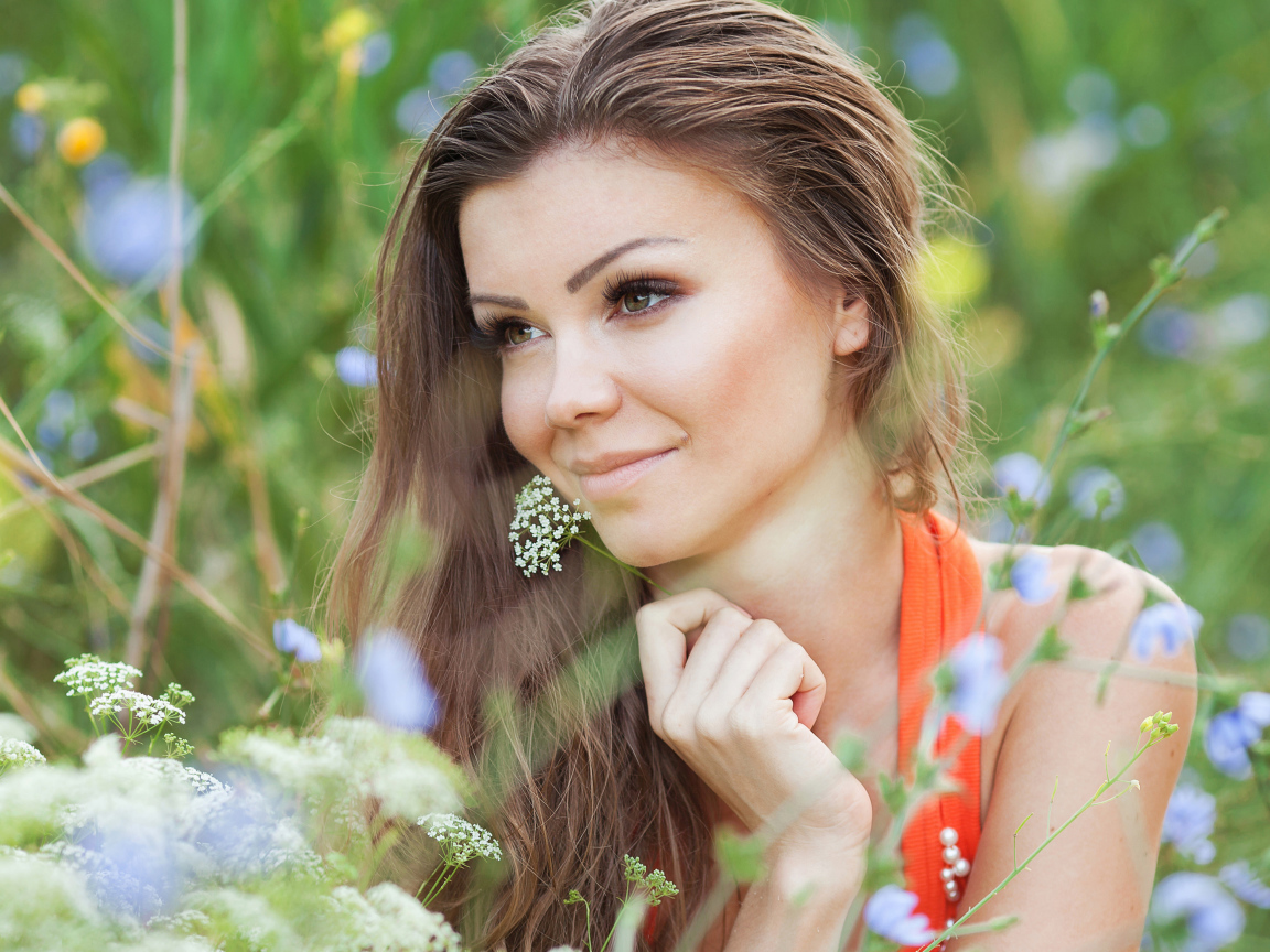 Красивая нежная девушка лежит в цветах на поле