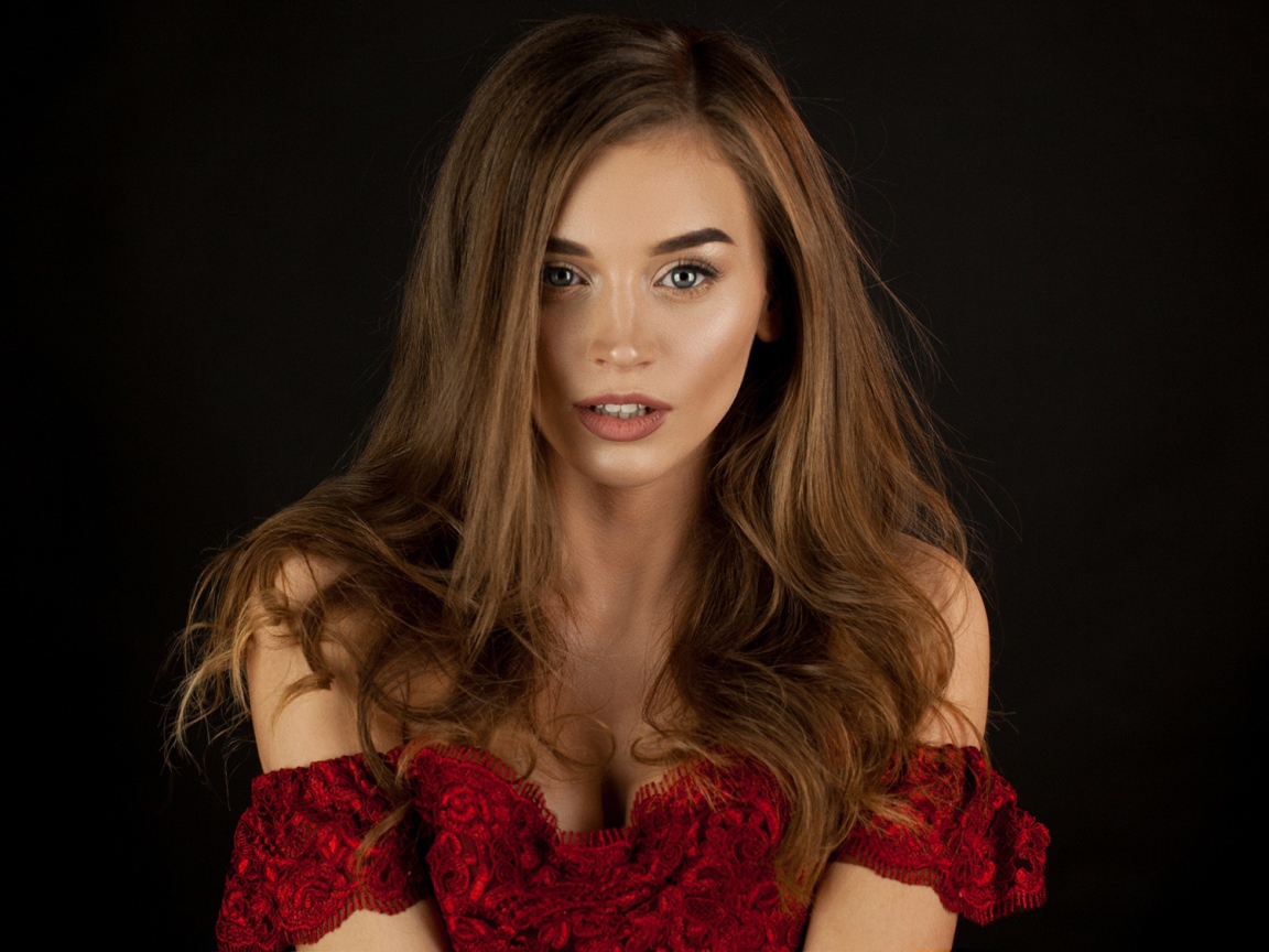 Красивая нежная длинноволосая шатенка в красном платье на черном фоне