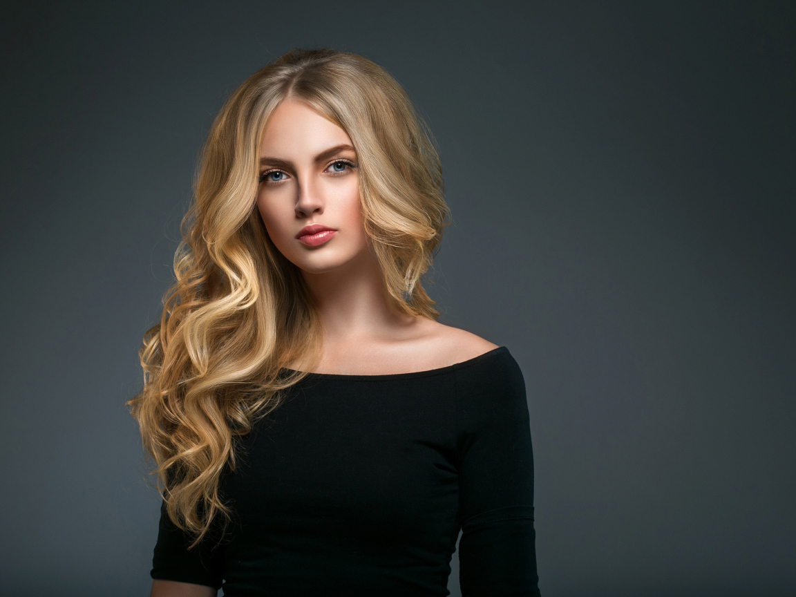 Красивая молодая девушка с длинными волосами в черном наряде на сером фоне