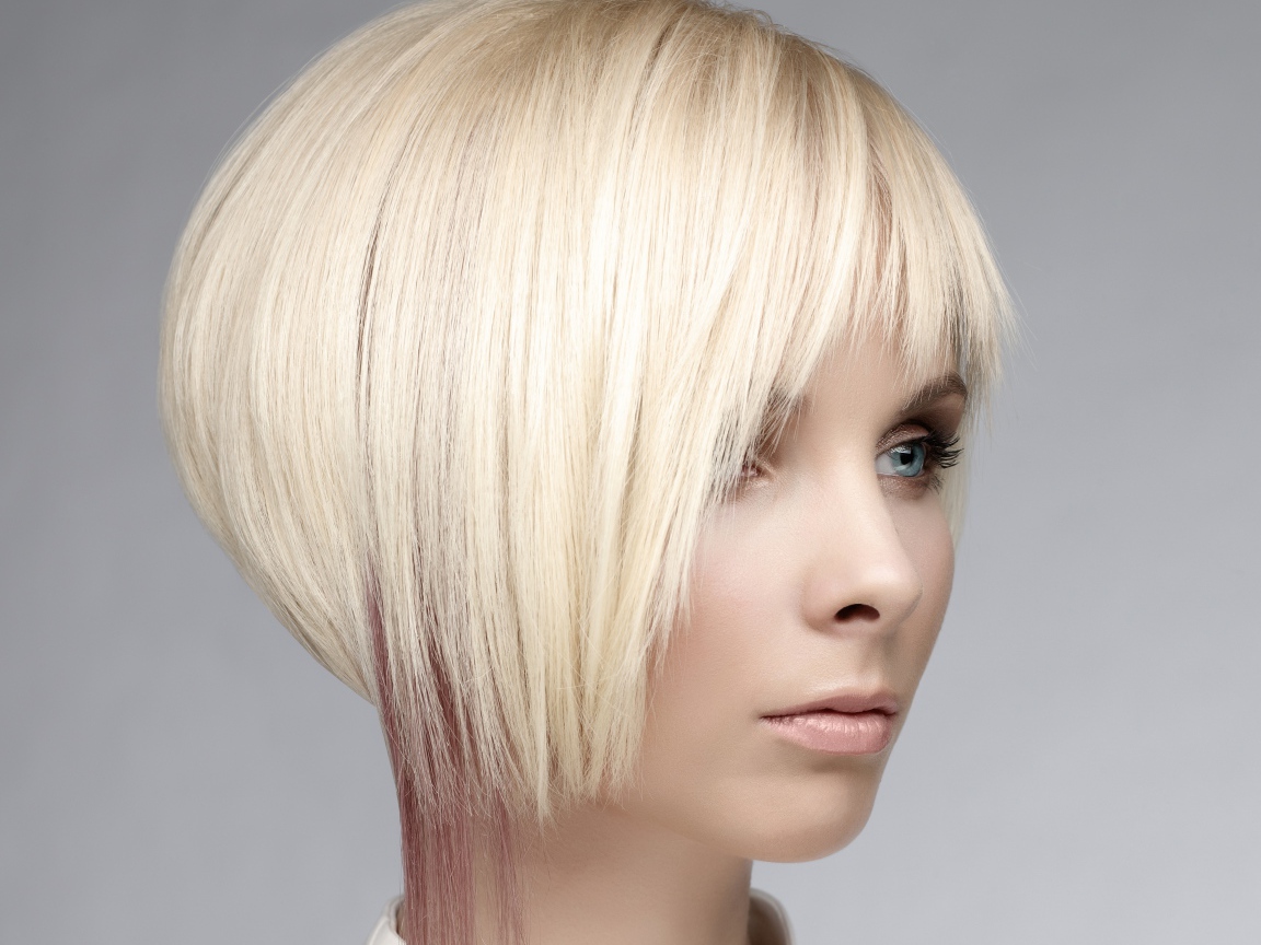 Голубоглазая девушка блондинка с короткой стрижкой на сером фоне