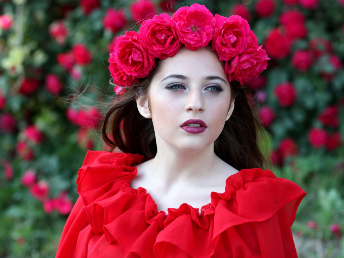 Яркая девушка в красном платье с венком из роз на голове