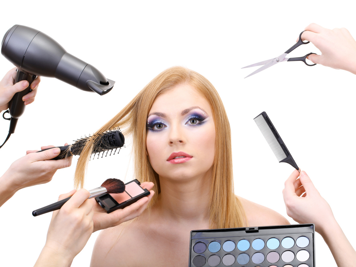 Девушке делают макияж и прическу на белом фоне