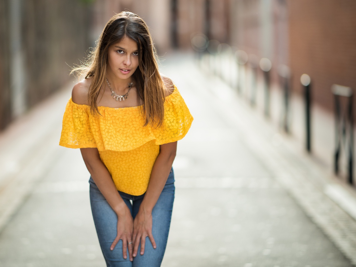 Девушка в джинсах стоит на улице 