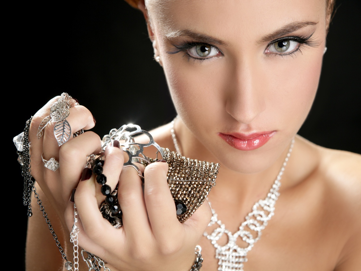 Девушка с длинными ресницами держит драгоценности в руке
