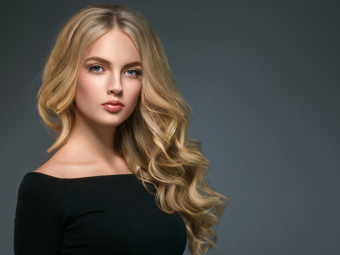 Длинноволосая блондинка с голубыми глазами на сером фоне