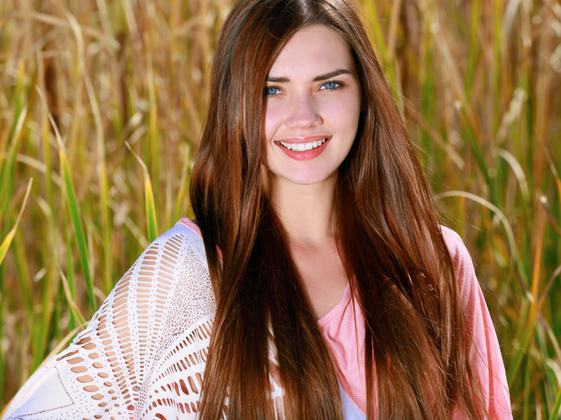 Улыбающаяся голубоглазая шатенка на поле